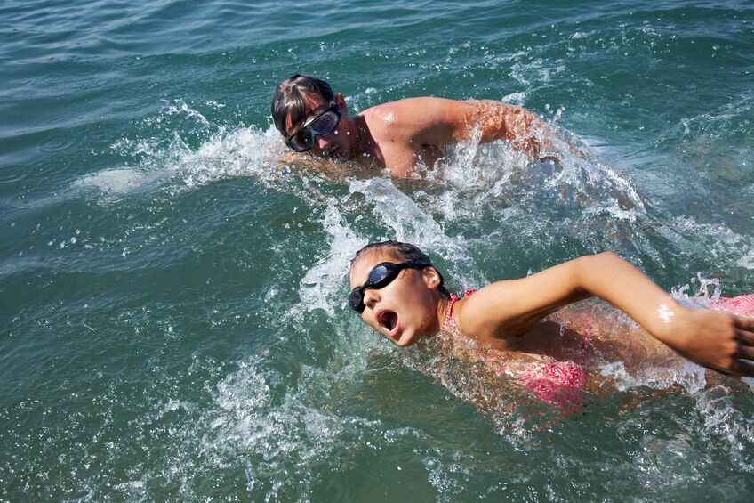 man and woman swimming together in open water